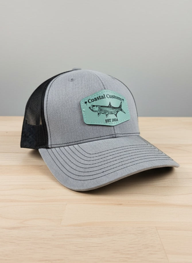 Gray and black cap with a green patch on a wooden surface and gray background