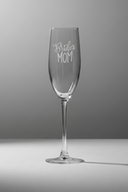 Clear champagne flute with 'Bride's Mom' engraving on a gray background