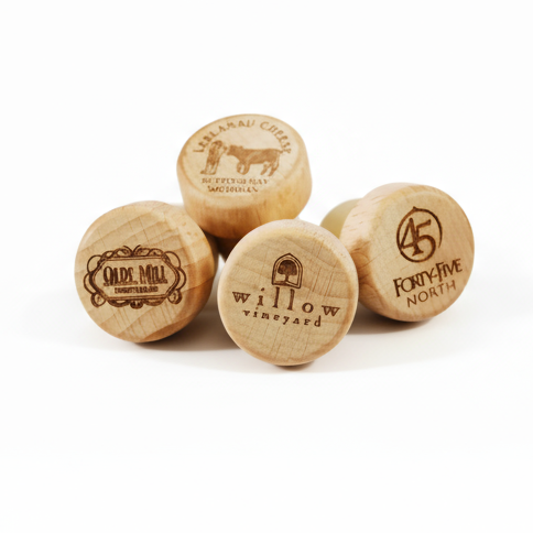 Four wooden wine bottle stoppers with engraved text and logos on a white background